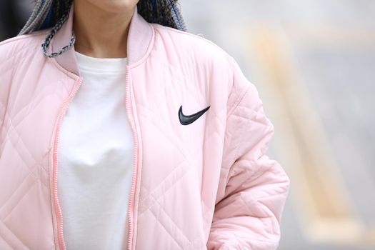 Happy stylish young hipster woman with long blue hair pink jacket, hat on the street in urban city.