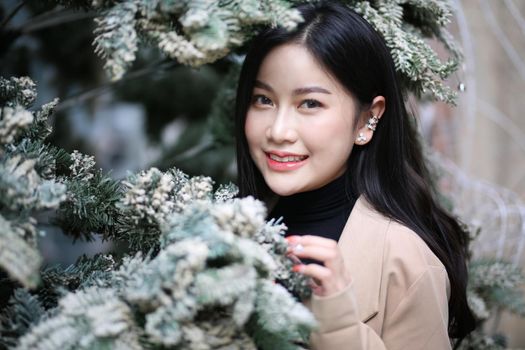 Portrait of young beautiful woman in winter clothes. while posing on snow background. Outdoor close-up photo of female model with romantic smile chilling in park in winter.