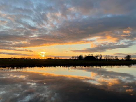 Winter sunset with clouds reflection in a lake around Sneek in Friesland The Netherlands