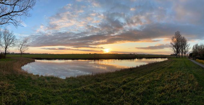 Winter sunset with clouds reflection in a lake around Sneek in Friesland The Netherlands