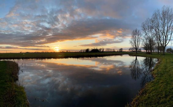 Winter sunset with clouds reflection in a lake around Sneek in Friesland The Netherlands