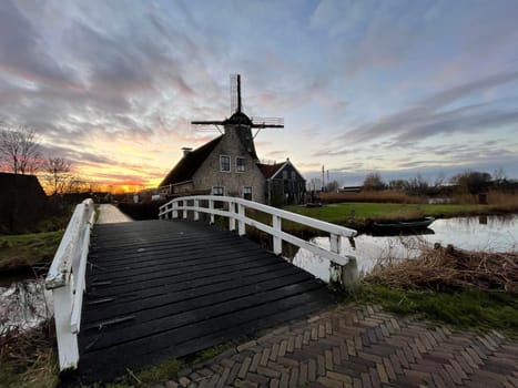 Bridge over a canal and a windmill in IJlst during sunset in Friesland The Netherlands