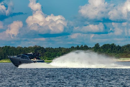 Grey speedboat moving fast by the river in Latvia. Water sport