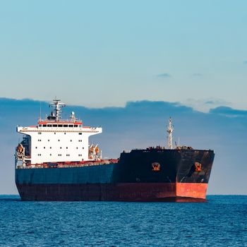 Black cargo ship moving in still Baltic sea water. Riga, Europe