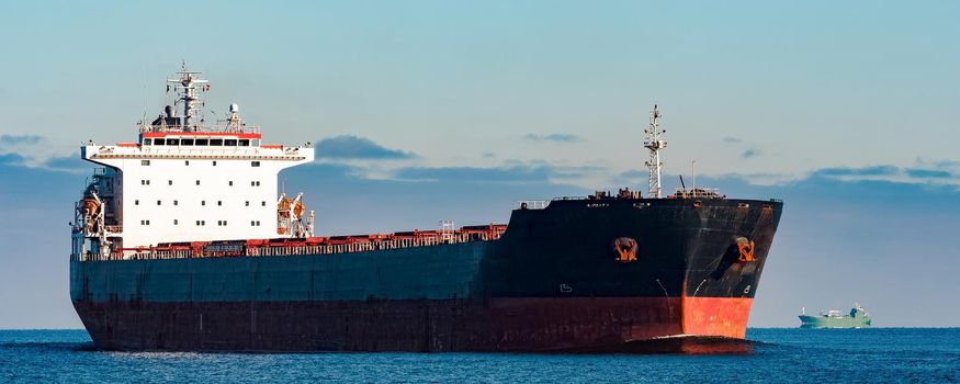 Black cargo ship moving in still Baltic sea water. Riga, Europe