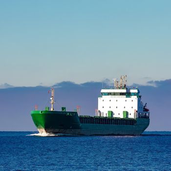 Green cargo ship moving in still water of Baltic sea