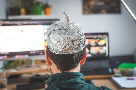 Young man is wearing aluminum cap, conspiracy theory concept