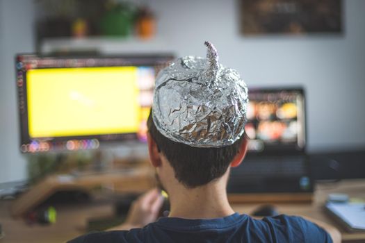 Young man is wearing aluminum cap, conspiracy theory concept