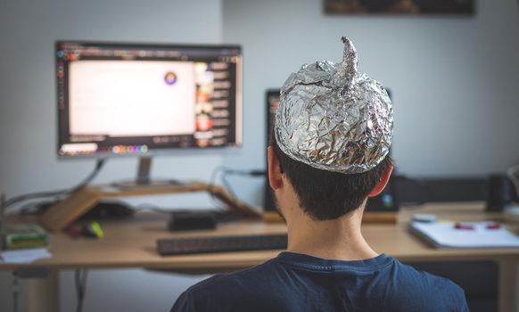 Young man is wearing aluminum cap, conspiracy theory concept