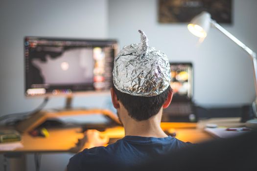 Young man is wearing aluminum cap, conspiracy theory concept
