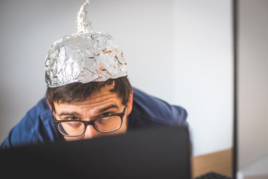 Young man is wearing aluminum cap, conspiracy theory concept