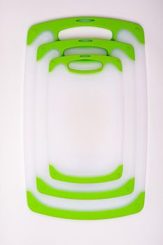 Set of white kitchen cutting boards with green handles for cooking. For cutting food, vegetables, meat, fish. Durable, professional, white plastic.