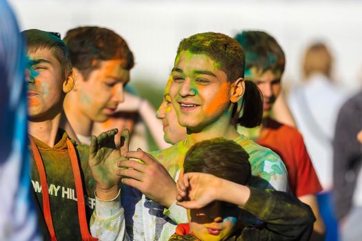 Russia, Moscow - June 25, 2017. Portrait of a young man with bright colors on his face. Laughs with happiness. Holi is a traditional holiday in India