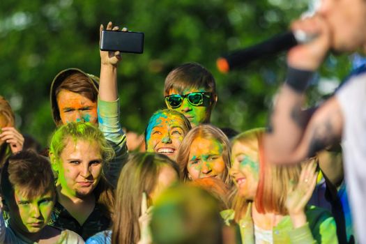 Russia, Moscow - June 25, 2017. Portrait of a girl with bright flowers on her face. Laughs with happiness. Holi is a traditional holiday in India