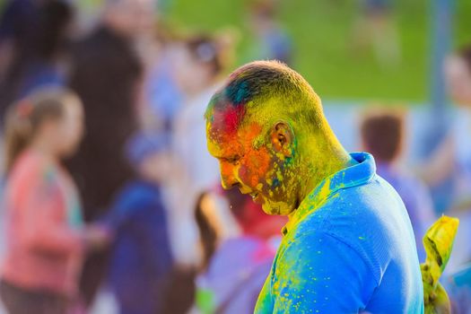 Russia, Moscow - June 25, 2017. A grown man with bright colors on his face. Laughs with happiness. Holi is a traditional holiday in India