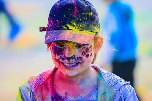 Russia, Moscow - June 25, 2017. Portrait of a girl with bright flowers on her face. Laughs with happiness. Holi is a traditional holiday in India