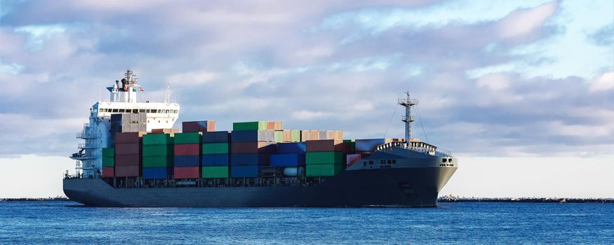 Modern grey container ship moving in still water