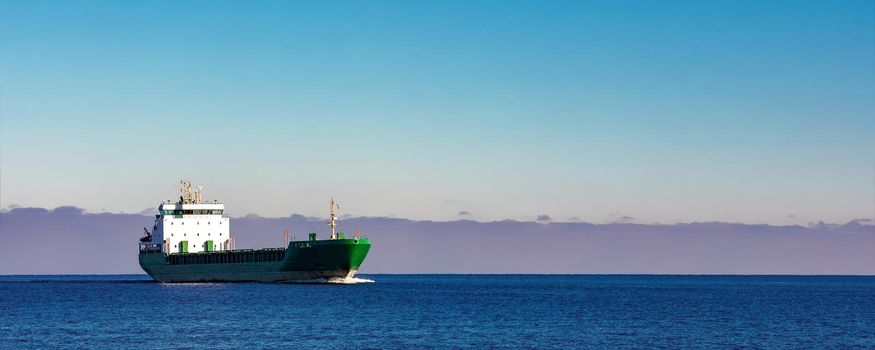 Green cargo ship moving in still water of Baltic sea