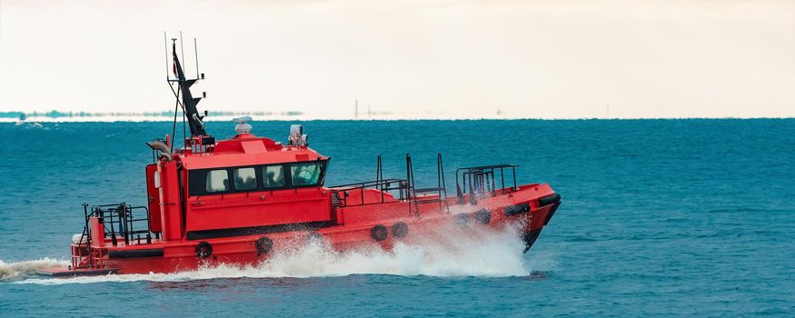 Red pilot ship sailing in still Baltic sea water