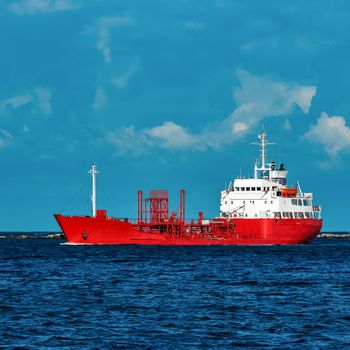 Red cargo tanker ship moving by the river