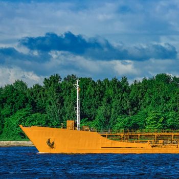 Yellow cargo tanker ship moving at the clear summer day