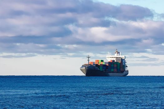 Modern grey container ship moving in still water