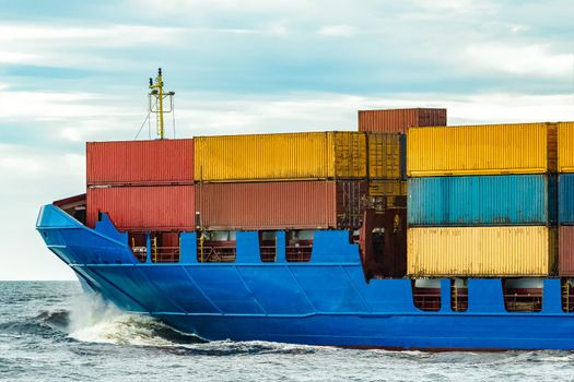 Blue cargo container ship fully loaded underway