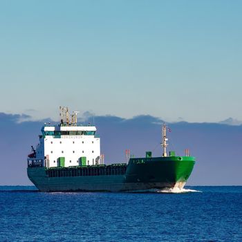 Green cargo ship moving in still water of Baltic sea