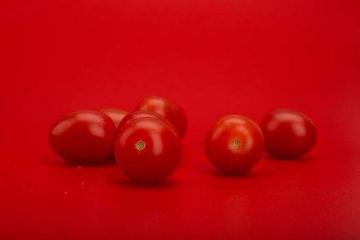 Red cherry tomatoes with drops of water against red background with copy space. Concept of organic vegetables, dieting or healthy lifestyle and wellness