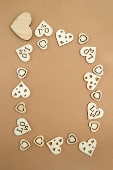 Wooden hearts on a pastel craft paper background in the form of a frame. Abstract background with wood cut shapes. Sainte Valentine. Copy space.
