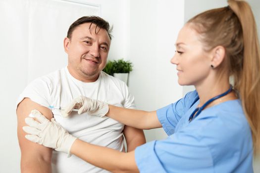 female doctor injecting into man's arm treatment hospital. High quality photo