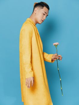 Side view of sexy Asian man in yellow coat on blue background Copy Space. High quality photo