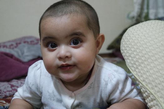 Baby girl with lovely face, big eyes and cute face gesture. Toddler baby making sweet activities