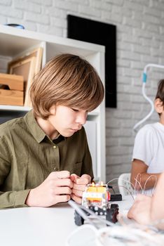 12 year old boy constructing a robot car sitting at the table