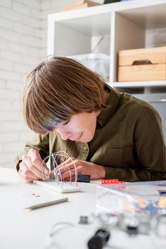 12 year old boy constructing a robot car sitting at the table playing with lights