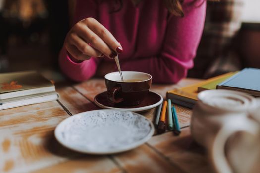 Cropped photo of young lady sitting in cafe while enjoying hot drink and studying