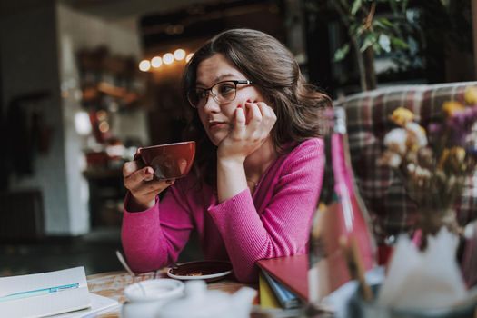 Pretty lady holding coffee and enjoying the day in cafe while and dreaming about something