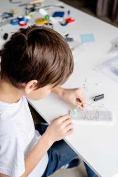 boy hands working with LED lights on experimental board for science project