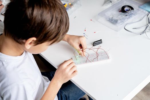 boy hands working with LED lights on experimental board for science project