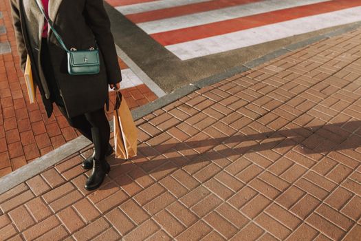 Cropped photo of woman holding bag while standing in the street during sunny day
