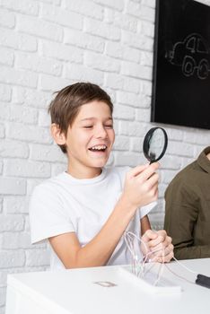 boy working with LED lights on experimental board for science project, using magnifying glass