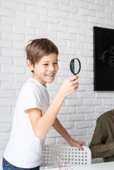 boy working with LED lights on experimental board for science project, using magnifying glass