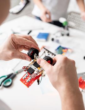 male hands constructing robot car at the workshop