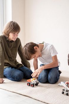 Young boys and having fun constructing robot cars together onthe rug
