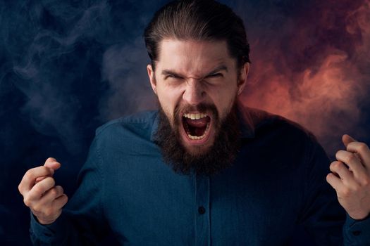 Emotional bearded man angry look shirt smoke in the background. High quality photo