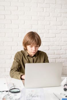 Young boy in green shirt working or studying on the laptop at home
