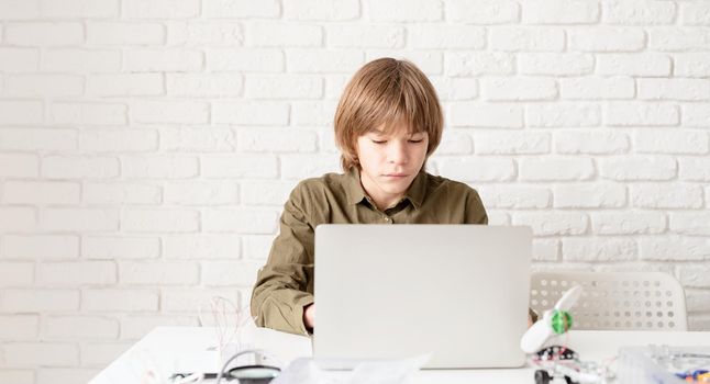 Young boy in green shirt working or studying on the laptop at home