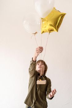 Happy boy playing with helium balloons