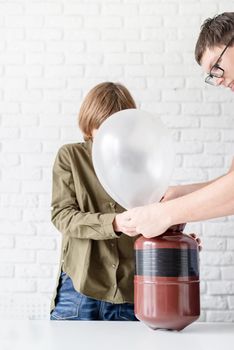 Funny boy blowing up a balloon with helium