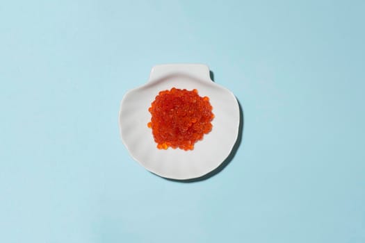 Porcelain plate with red caviar on a blue background.
